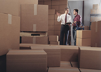 two men discuss boxes in a warehouse